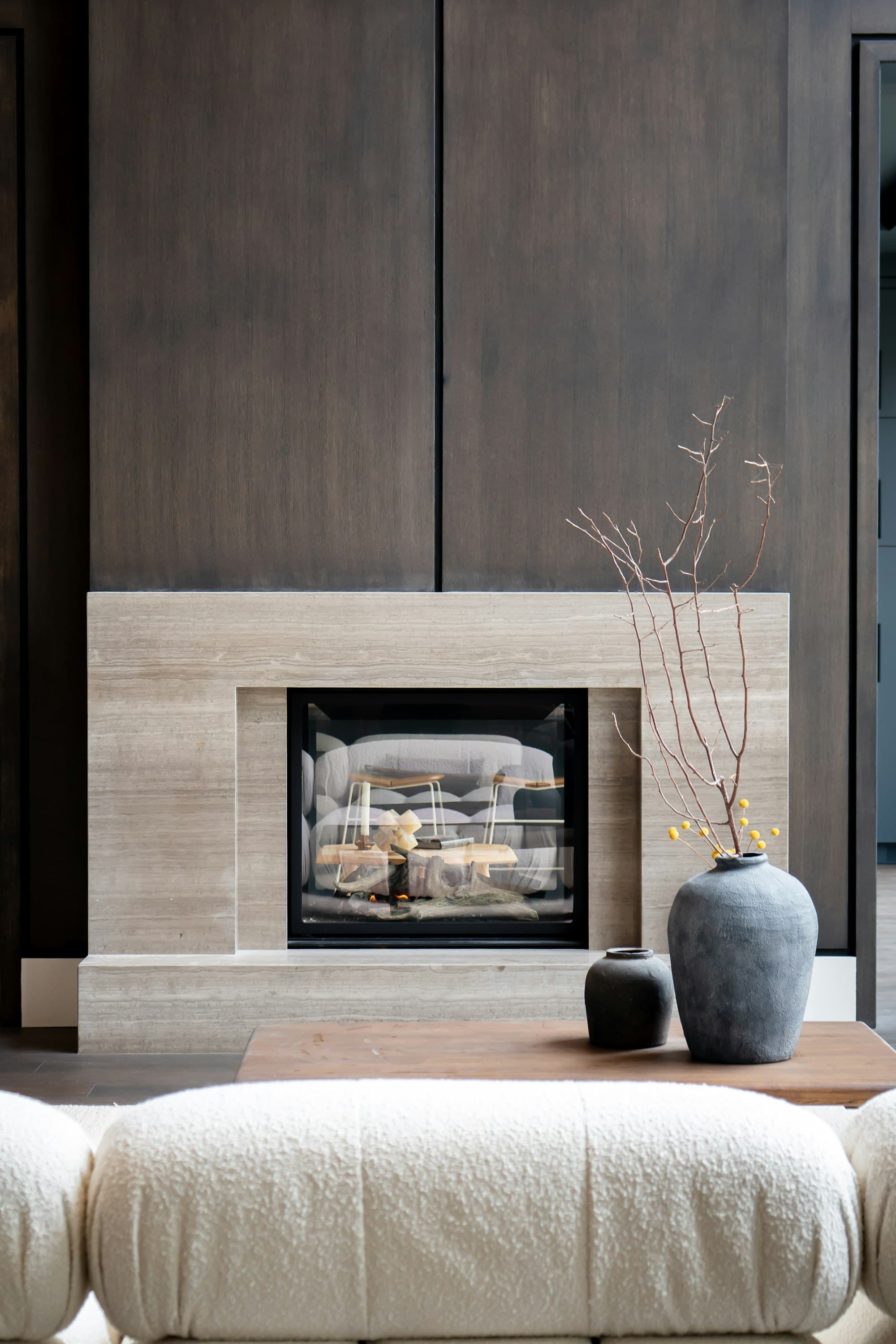 A walnut-panelled living room with a linear fireplace set into a stone surround